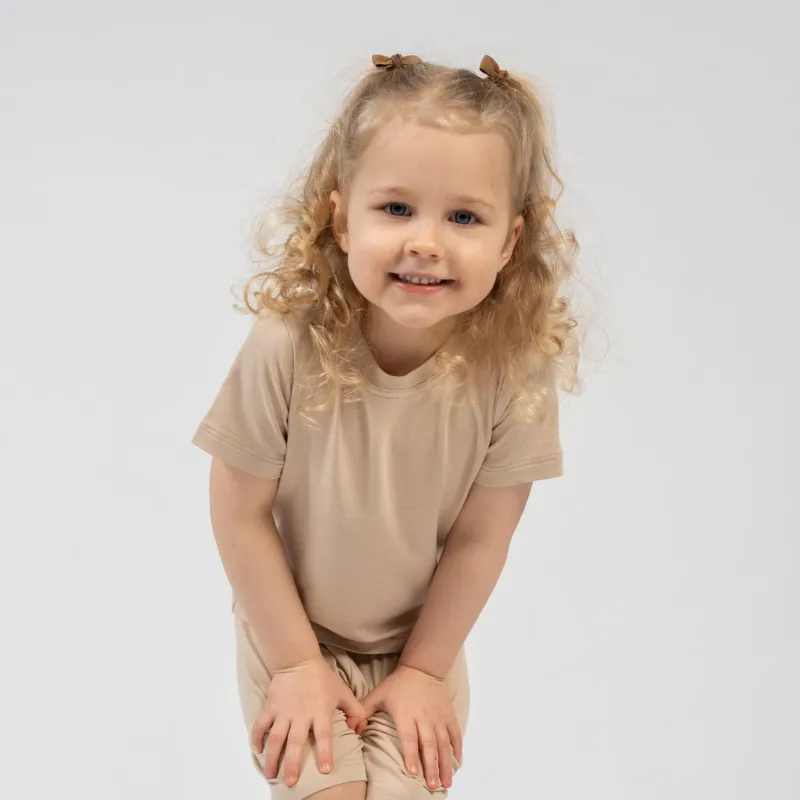 Kids beige bamboo clothing set – girl squatting in soft breathable t-shirt and shorts