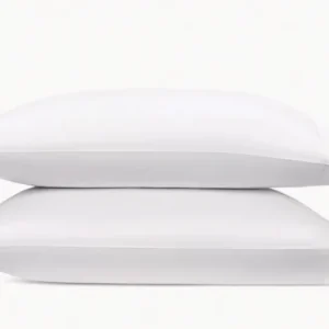 Two neatly stacked white pillows against a soft, neutral background, showcasing their plush, inviting contours, and elegant hemstitch. Featuring Bergamo Hemstitch bedding by Matouk. Available at Linen Society.