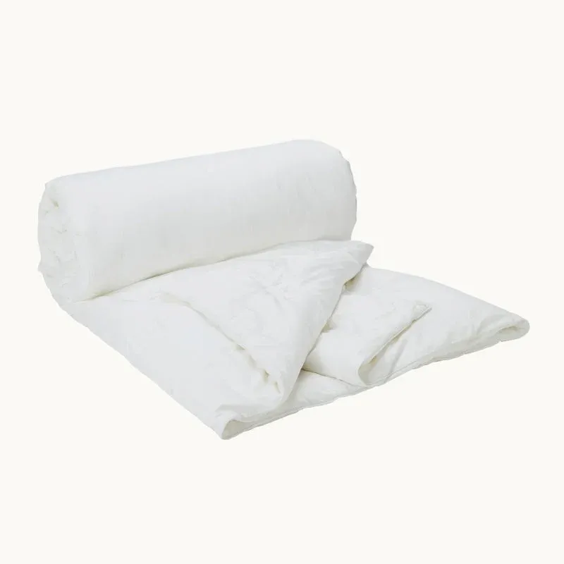 Gingerlily London ivory silk filled comforter, rolled and folded on neutral background.