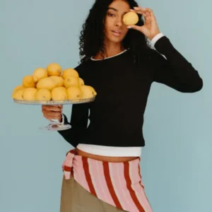 Model wearing TBCo Merino Wool Triangle Scarf in Pink & Rust Stripe tied at waist with relaxed trousers and black top