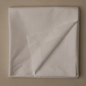 LETTO Sea Island Percale flat sheet folded in white, corner turned back on beige surface.